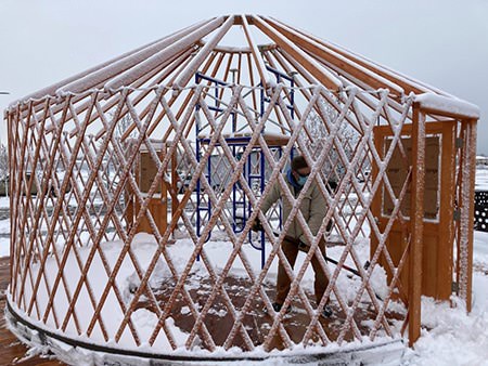 Snow-covered wooden yurt frame