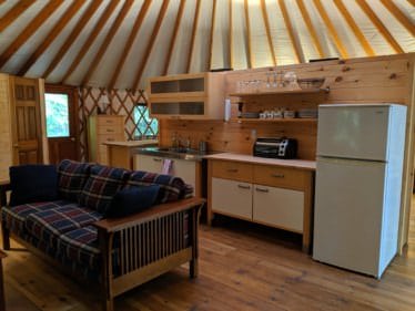 Kitchen and sofa beneath yurt rafters