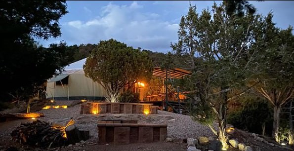 Yurt illuminated at dusk among trees