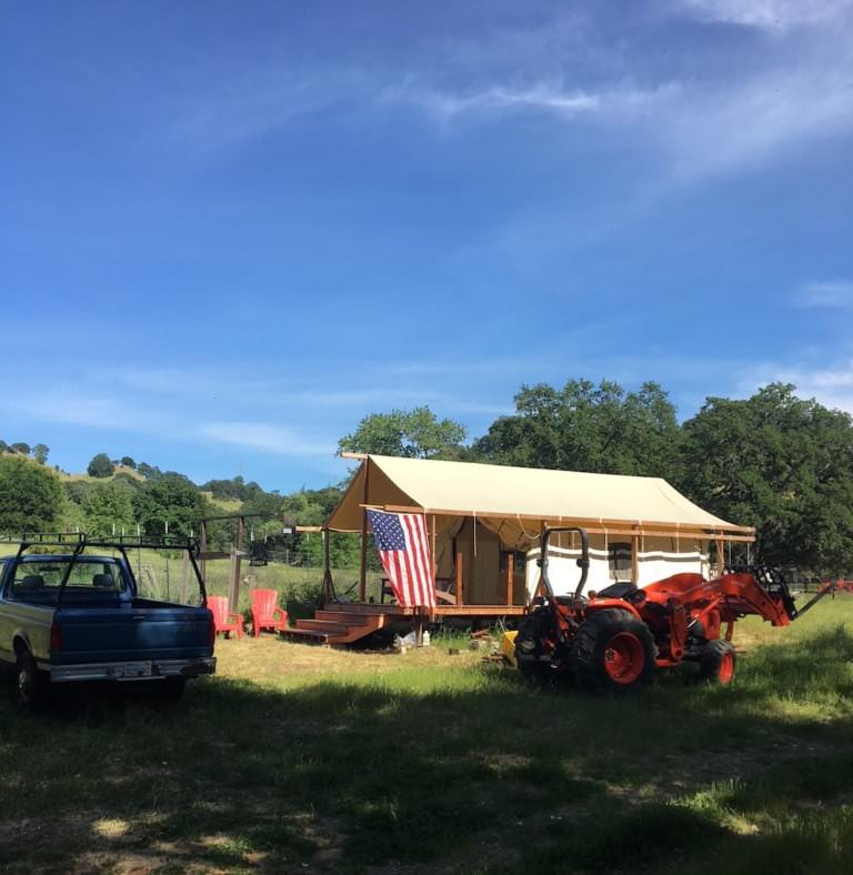 Canvas tent on a platform beside vehicles