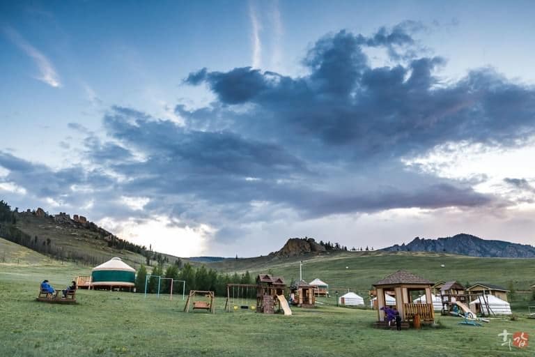 Yurts beneath a cloudy mountain sky