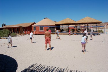 People playing on a beach beside yurts