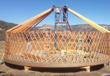 Workers fitting roof rafters to a yurt frame